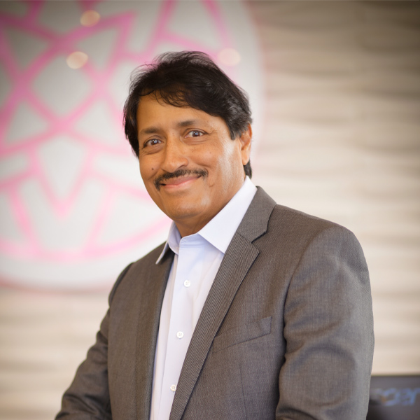 Dr. Dev ManiSundaram in a grey suit in front of practice logo in Flowood practice